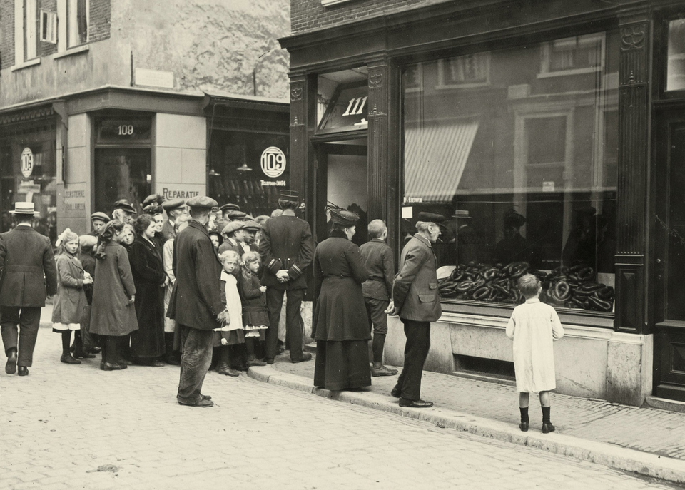 Mensen kijken een vitrine in die vol ligt met worsten.